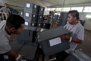 Hombres cargan las últimas papeletas de votación enviadas a los centros electorales.
