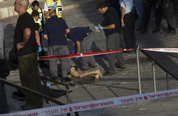 Agentes de policía israelíes inspeccionan el cuerpo del palestino asesinado en la puerta de Damasco.