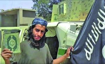 El belga Abdelhamid Abaaoud, sostiene el libro sagrado de los musulmanes, Corán, y la bandera del Estado Islámico.