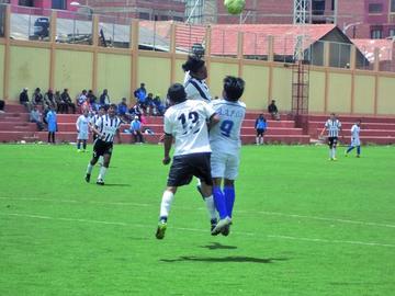 Los futbolistas se disputan el esférico.