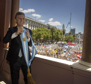 El nuevo presidente argentino sostiene la banda presidencial en el balcón de la Casa Rosada.