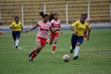 Las futbolistas se disputan el balón.