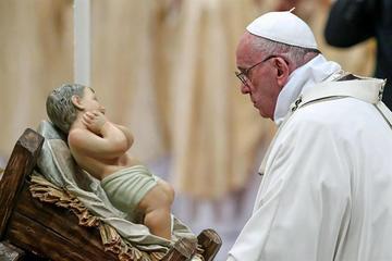 Francisco mira una figura de un niño Jesús durante una por la celebración de la Navidad.