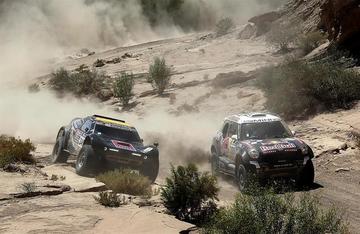 El piloto catari Nasser Al-Attiyah (d), del equipo Mini, adelanta al sudafricano Mark Corbett (i)