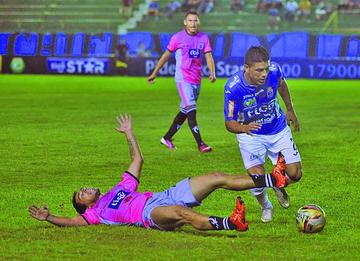 Miguel Hurtado (d) se lleva el esférico ante uno de sus rivales que esta en el suelo.