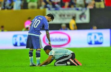 Messi (i) firma una camiseta a un aficionado (d) que entró al campo.