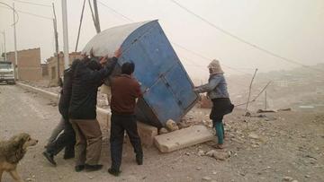 Con la ayuda de vecinos se hace parar una caseta que fue volteada por la fuerza del viento.