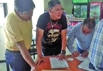 Los dirigentes Antonio Decormis (i) y Oscar Careaga (d) junto al técnico Carlos Fabián Leeb (c) en la firma de contrato.