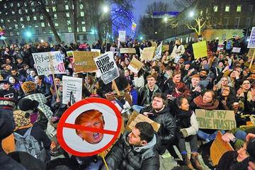 Cientos de personas sostienen carteles con mensajes en contra del presidente estadounidense en el Reino Unido.