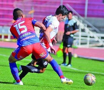 Edson Pérez, de la banda roja, protege la pelota ante la marca de su rival.