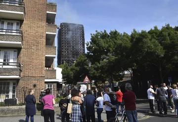 Varios residentes observan la Torre Grenfell tras apagarse el fuego.
