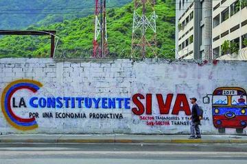 Un hombre camina junto a una pared decorada con propaganda de la Asamblea Nacional Constituyente.
