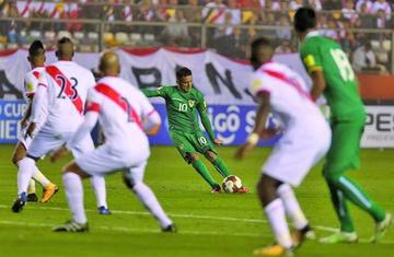 El mediocampista Jhasmany Campos patea el balón ante los jugadores de Perú.