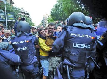 Agentes antidisturbios de la Policía Nacional forman un cordón de seguridad frente al colegio Ramón Llull de Barcelona.