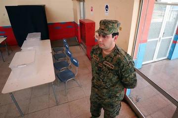 Militares prestan guardia en la sede de un colegio que recibirá a los electores en esta jornada.