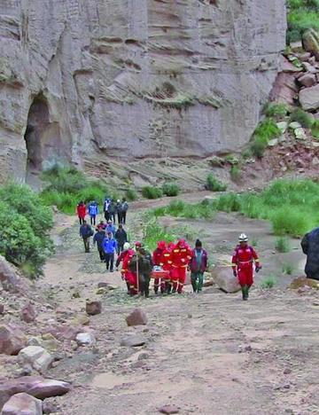 Los policías sacan el cuerpo de Reader por el cañadón de Mondragón.