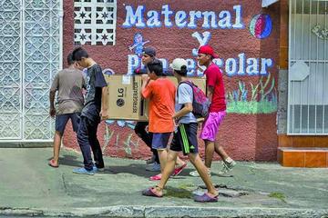 Varios jóvenes cargan artículos para el hogar durante un saqueo.