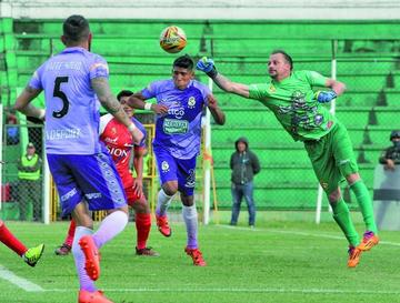El portero lila, Marcelo Robledo, despeja el balón.
