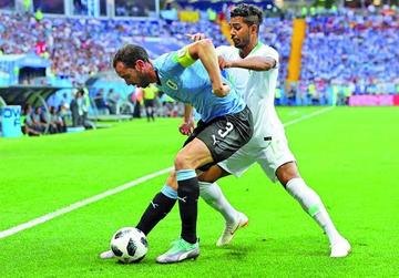 Diego Godin, de Uruguay, protege la pelota ante la marca de su rival.