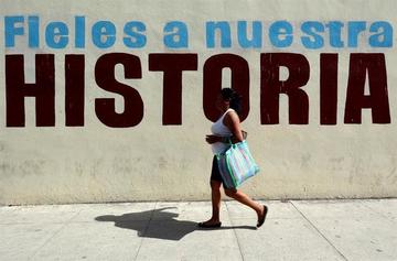 Una mujer pasa junto a un cartel alusivo a la revolucion cubana.