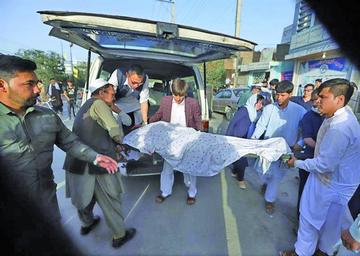 Varias personas cargan en un coche el cuerpo sin vida de un hombre tras un atentado ocurrido en Kabul.