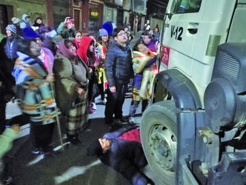 Un comerciantes se mete entre las llantas del un volquete para impedir su circulación.