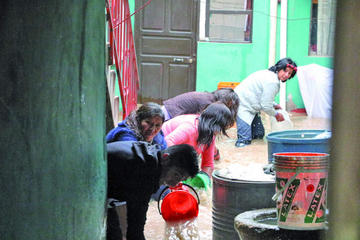 Los dueños de una vivienda de la calle Hoyos sacan el agua con baldes.