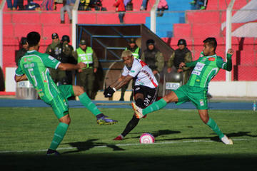 Harold Reina (c) remata el balón ante la presión de dos rivales.