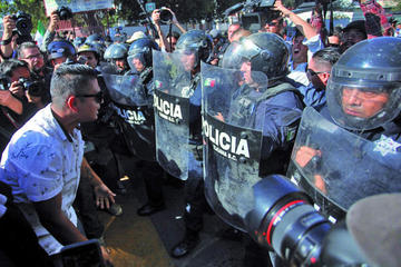 Manifestantes increpan a policías durante una protesta en contra de la presencia de migrantes.