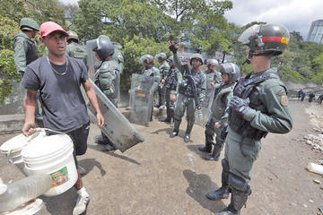 Miembros de la Guardia Nacional tratan de dispersar a las personas que tratan de recolectar agua.