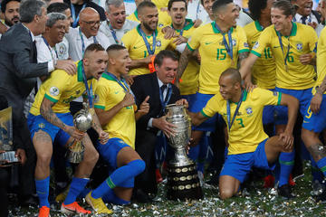El presidente de Brasil y los jugadores celebran con el trofeo de la Copa América.