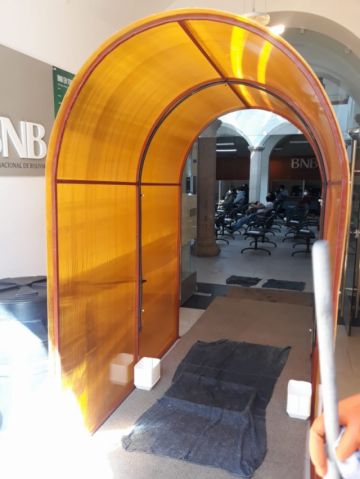 Está en la entrada a la entidad bancaria.
