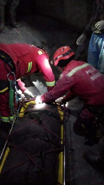 Bomberos sujetan el cuerpo para extraerlo.