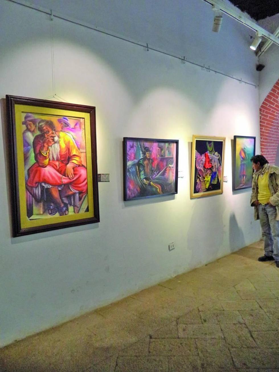 Varias obras son observadas por los visitantes.