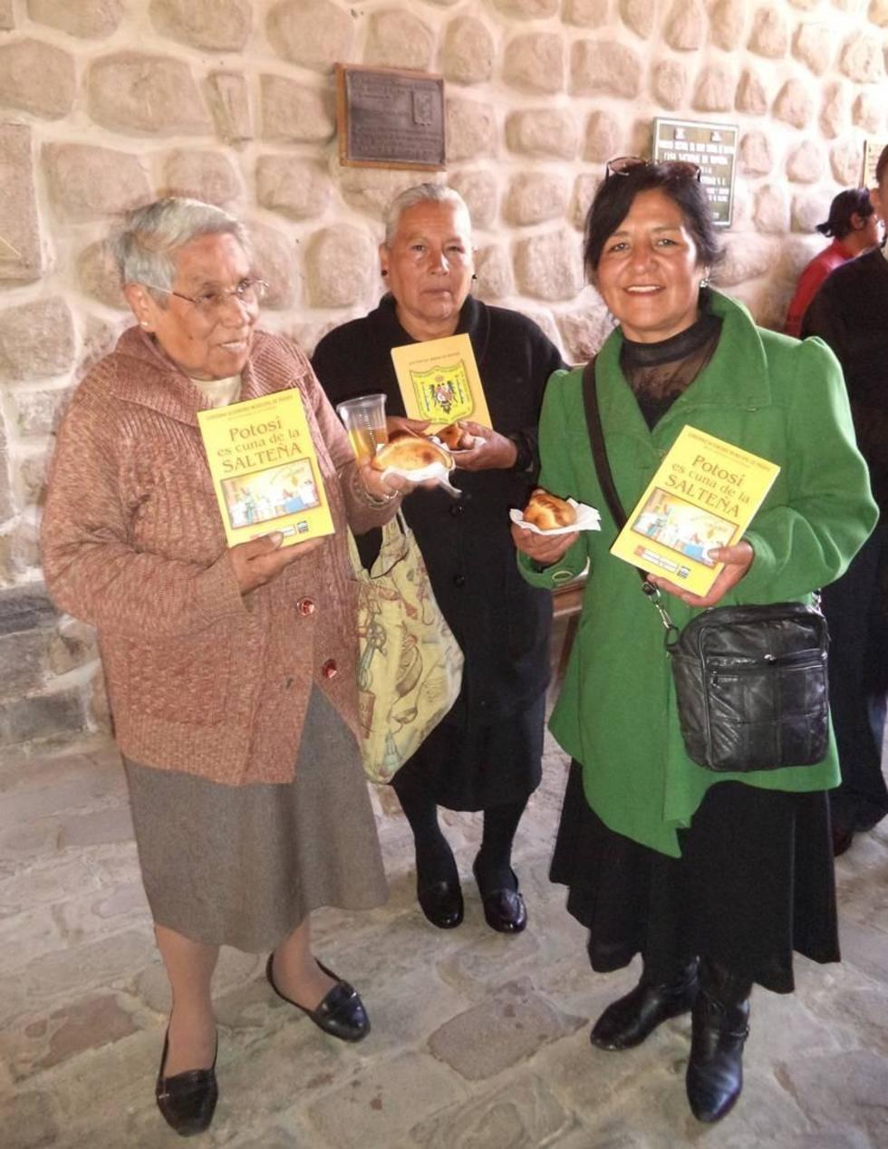 La población muestra el libro, la salteña y un refresco popular.