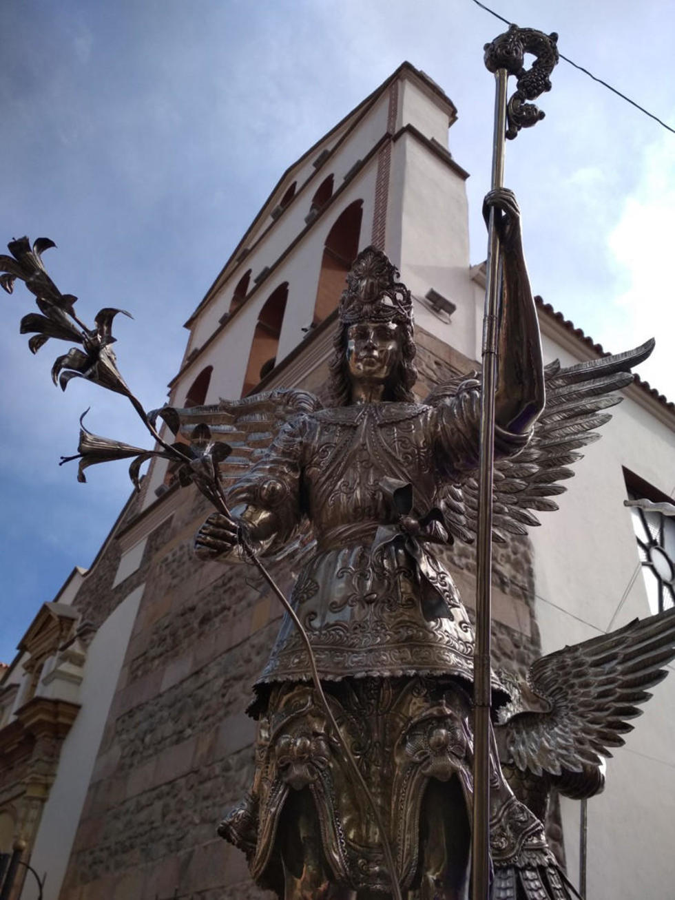 Un arcángel de plata con el fondo de la torre de Santo Domingo.