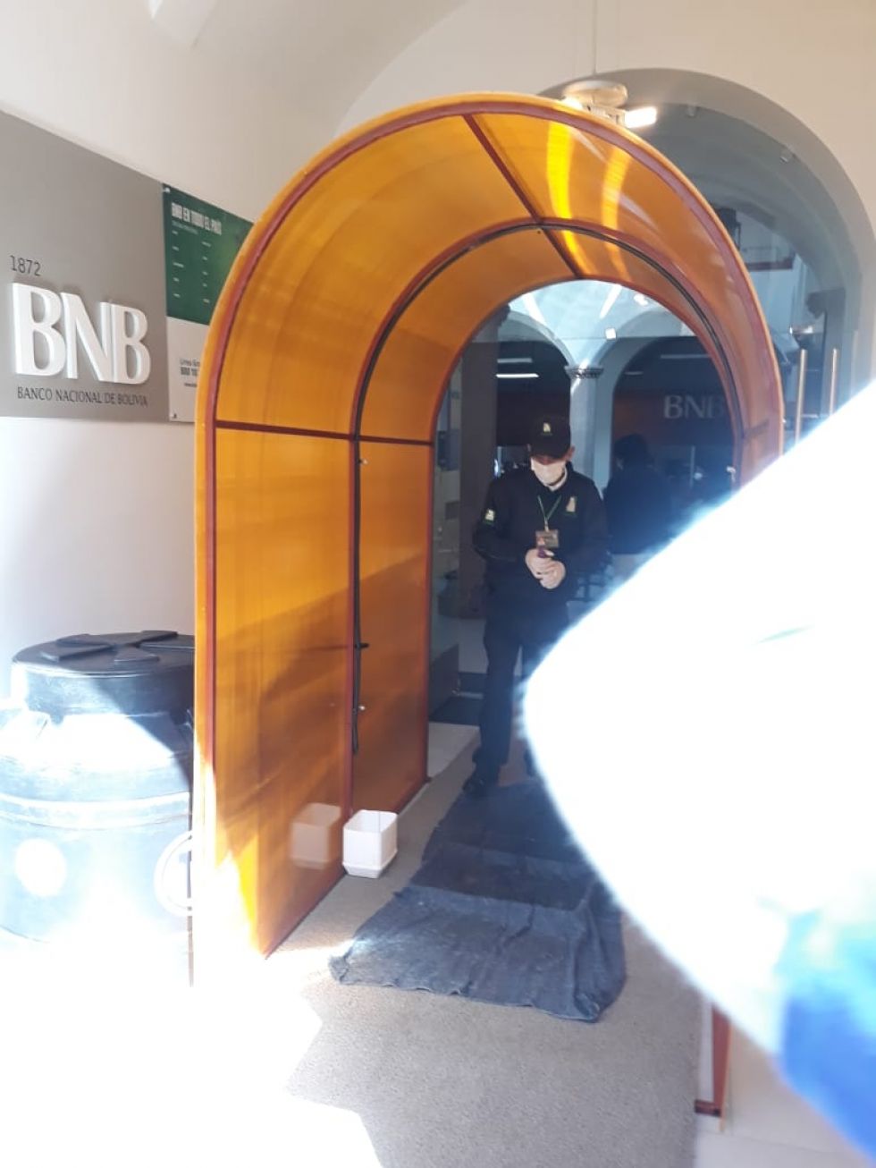 Está en la entrada a la entidad bancaria.