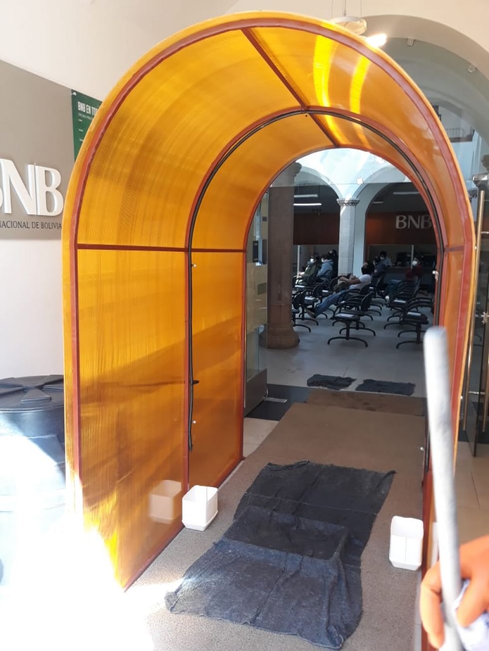 Está en la entrada a la entidad bancaria.
