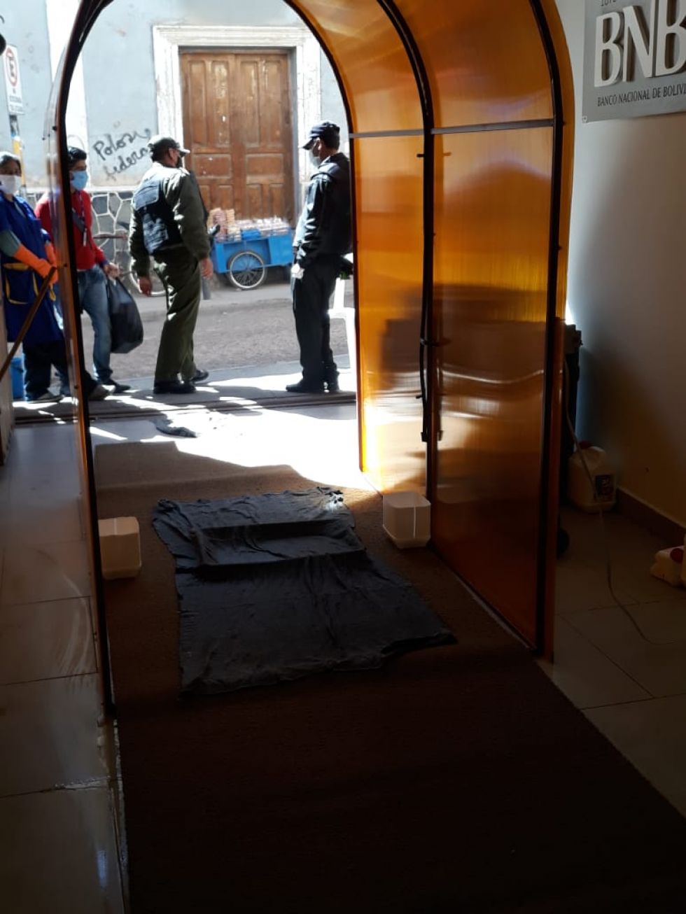 Está en la entrada a la entidad bancaria.