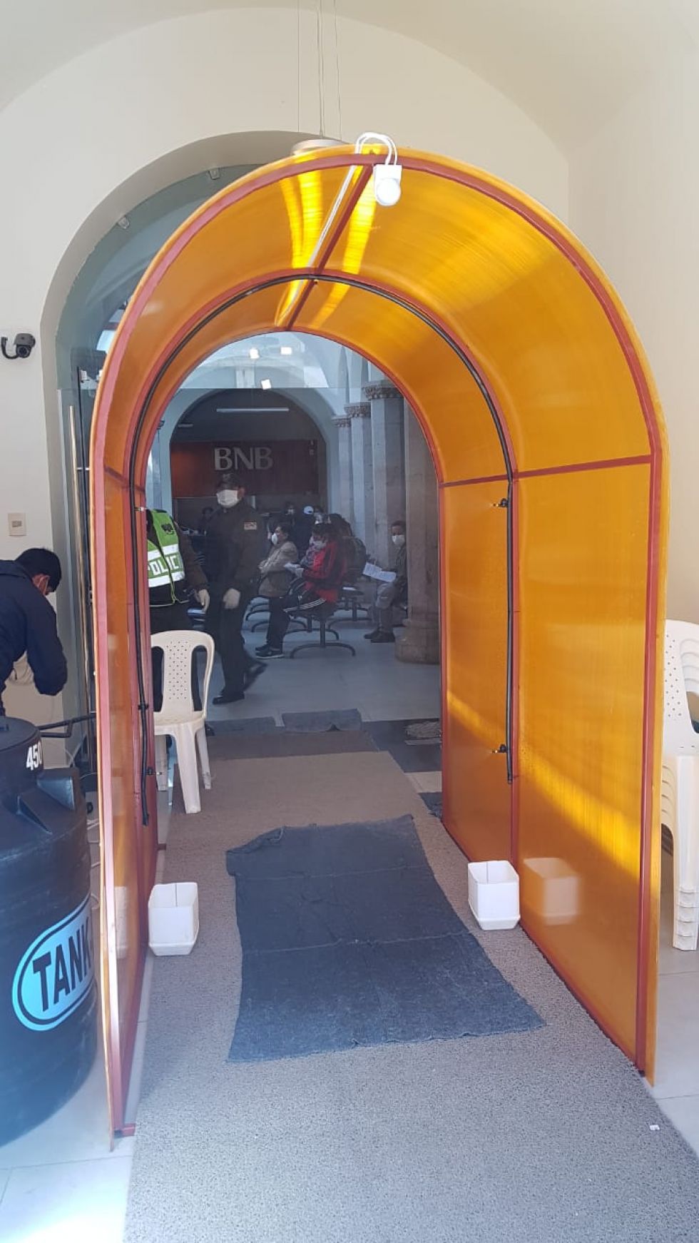 Está en la entrada a la entidad bancaria.